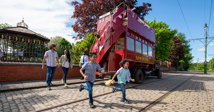 family of four walking across street at Beamish Museum with tram in background